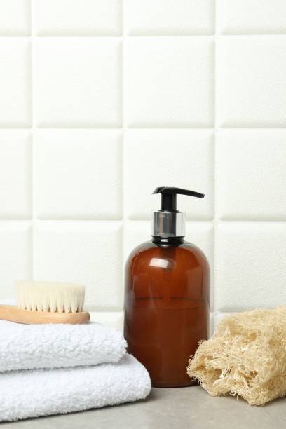 istock Different bath accessories and cosmetic bottle on gray table near white tiled wall 2200986677