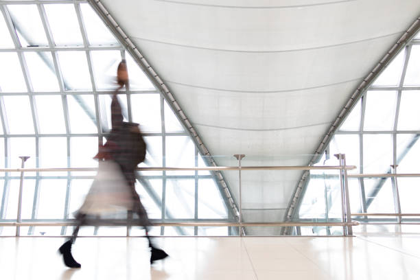 istock An unidentifiable person walking in motion blur on white corridor with large windows. Blurred people walking in a modern building. 2200991648