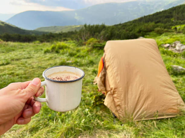 istock Hand holds white enamel mug filled with hot beverage, dusted with cocoa, 2200997468