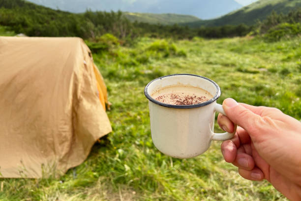 istock Hand holds white enamel mug filled with hot beverage, dusted with cocoa, 2200997490