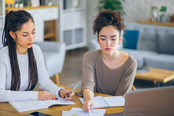 istock Two roommates studying together at home, helping each other sitting in a table at home 2201000944