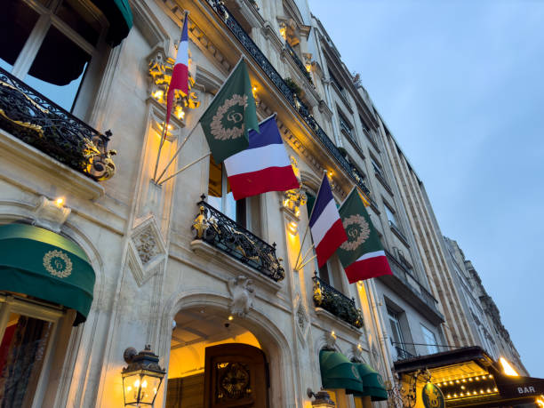 Paris,France-04.02.2025 Two French flags stand proudly outside an ornate building in Paris as twilight approaches, illuminating the charming architecture and vibrant atmosphere.