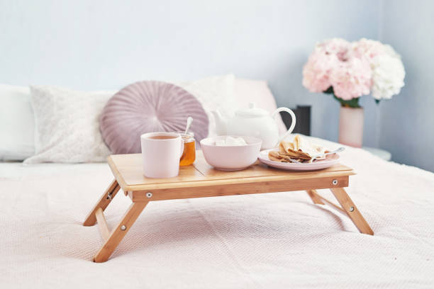 istock Breakfast in bed in hotel room. Accommodation. Breakfast in bed with tea cup with pancakes on tray on bed background top view. Copy Space. Romantic valentine's day breakfast. Cozy breakfast Maslenitsa 2201004003