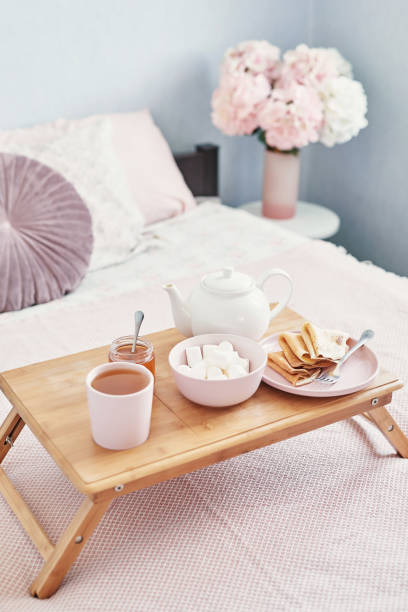 istock Breakfast in bed in hotel room. Accommodation. Breakfast in bed with tea cup with pancakes on tray on bed background top view. Copy Space. Romantic valentine's day breakfast. Cozy breakfast Maslenitsa 2201004062