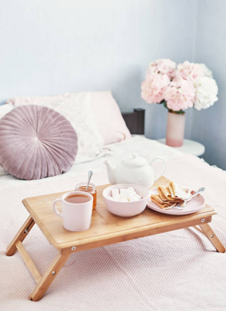 istock Breakfast in bed in hotel room. Accommodation. Breakfast in bed with tea cup with pancakes on tray on bed background top view. Copy Space. Romantic valentine's day breakfast. Cozy breakfast Maslenitsa 2201004093