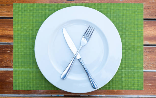 istock Top view of fork and knife on a plate, empty white plate on a restaurant table, Fine dine table set up, Restaurant table background 2201007722
