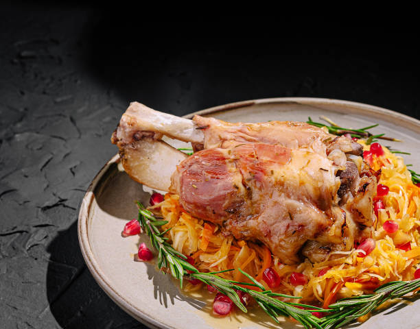 istock Savory meat dish garnished with pomegranate and herbs on a rustic plate with green foliage 2201008356
