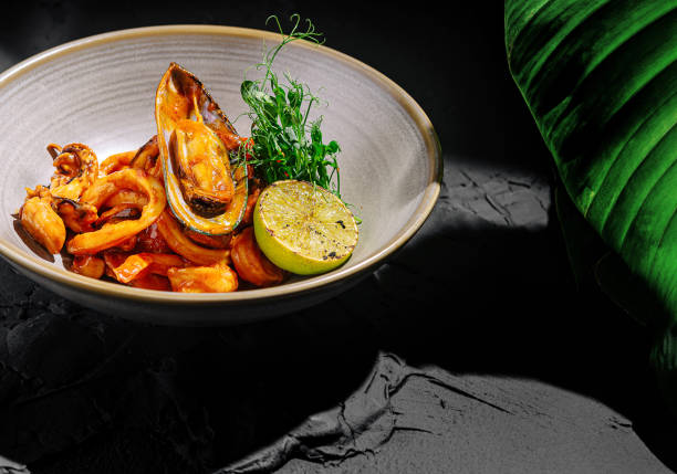 istock Delicious seafood dish with fresh lime and herbs in a stylish bowl on a dark textured surface 2201009270