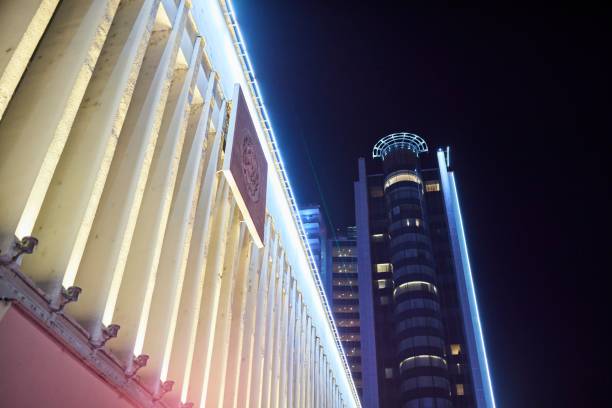 Krasnodar, Russia. - September 28, 2024: A tall building with a large window and a neon sign on top. The building is lit up at night