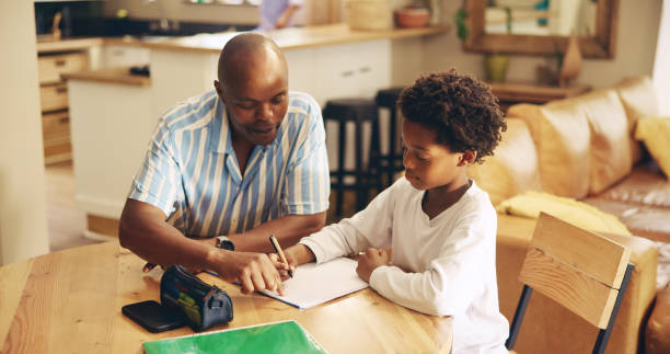 istock Help, studying and child with dad, notebook and advice for son, growth and development with education. Bonding, black man and assistance for homework, writing knowledge for kid, pointing and home 2201017470