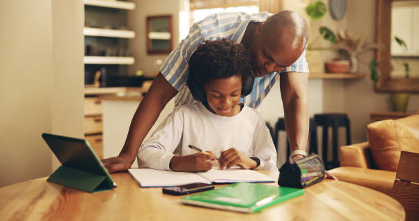 istock Studying, help and child with headphones, dad and education for boy, growth and development in home. Bonding, black man and assistance for homework, notebook and knowledge for exam, son and house 2201017476