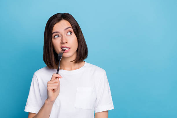 istock Photo of young  girl wonderd dreamy look empty space biting table fork isolated over blue color background 2201018388