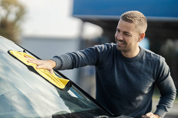 istock A man is polishing windshield on a car with microfiber cloth at car wash. 2201018598
