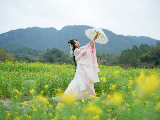 Two women in traditional Japanese clothing are playing a game of badminton in a park. The setting is serene and peaceful, with trees and bushes surrounding the area. The women are focused on the game