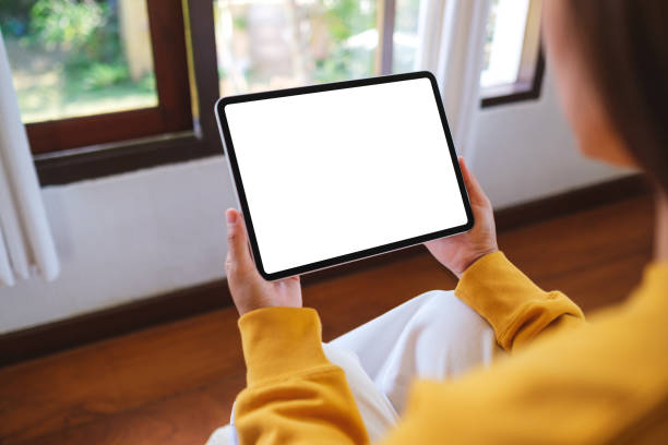 istock Mockup image of a woman holding tablet with blank desktop white screen at home 2201019975
