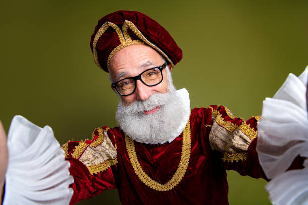istock Elderly man in medieval noble costume posing joyfully against a khaki background 2201022321