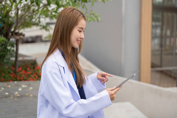 istock Female doctor in lab coat using tablet outdoors, symbolizing modern healthcare practices. 2201022467