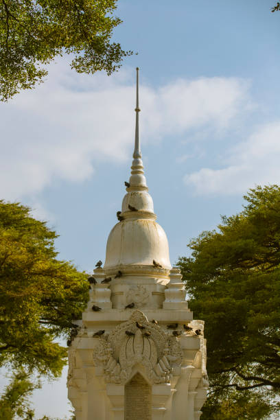 istock Ornate Thai Temple Spire Framed by Trees blue sky and clouds daytime pagoda 2201025432