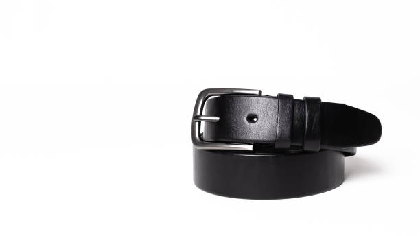 istock Twisted black leather belt with matted metal buckle isolated on white background. Fastened fashionable unisex, man or woman accessory for trousers, jeans, dress. Male luxury strap. Haberdashery goods 2201026378