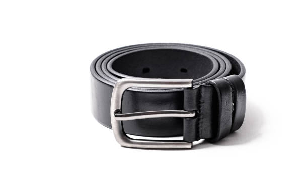 istock Twisted black leather belt with matted metal buckle isolated on white background. Fastened fashionable unisex, man or woman accessory for trousers, jeans, dress. Male luxury strap. Haberdashery goods 2201027795