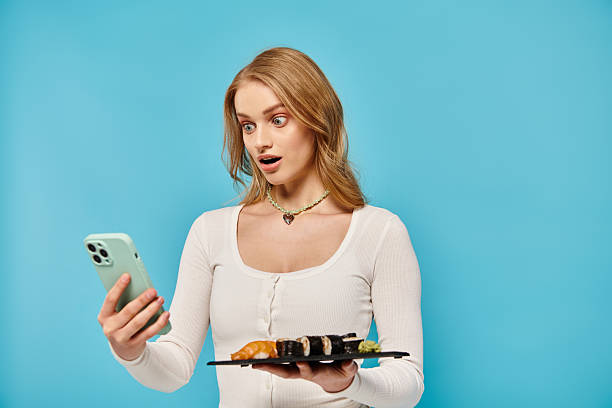 istock Young woman overwhelmed with emotions while enjoying sushi and using her phone 2201029828
