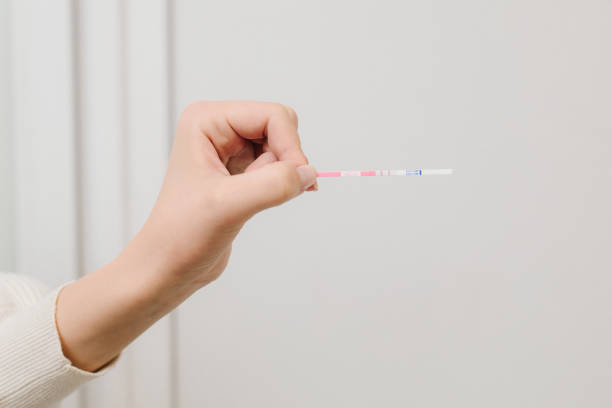 istock Positive pregnancy test on white background. Future mother holds positive pregnancy test with positive result. 2201030221