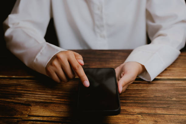 istock Person Using Smartphone on Wooden Table in Soft Light Atmosphere 2201031038