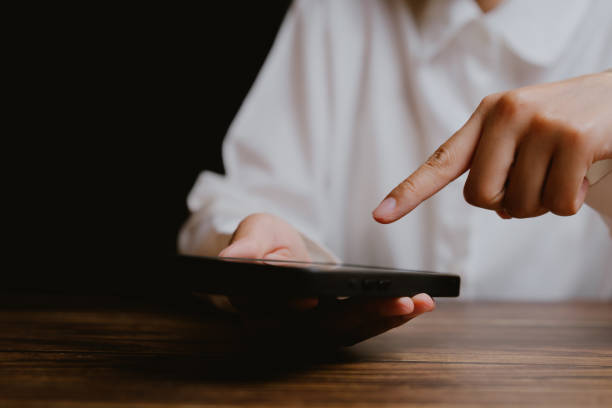 istock Woman Using Smartphone with Finger Touching Screen in Low Light 2201031080