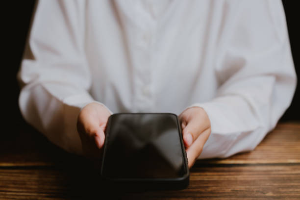 Person Holding Smartphone with Blank Screen in Casual Indoor Setting