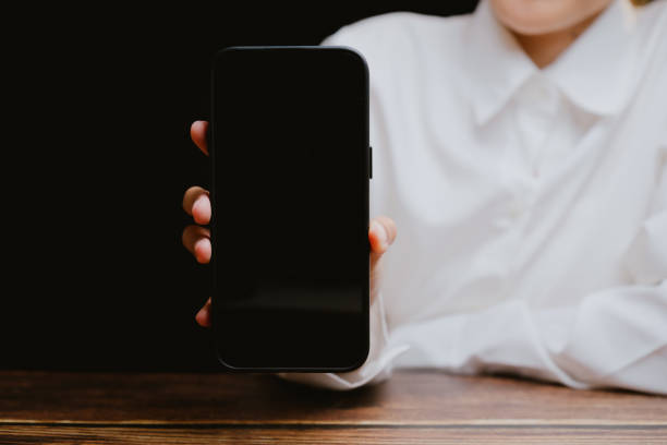 istock Person Holding Empty Smartphone against Black Background 2201031091