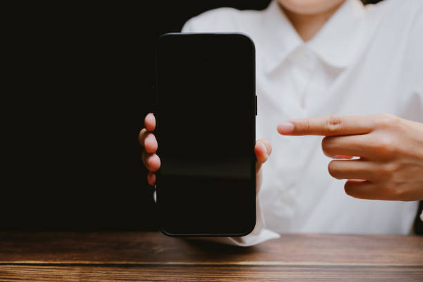 istock Person Holding Blank Smartphone in Dark Background for Display Use 2201031092