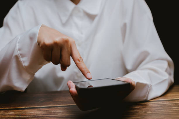 istock Person Using Smartphone with Finger Tapping Screen in Dark Room 2201031133