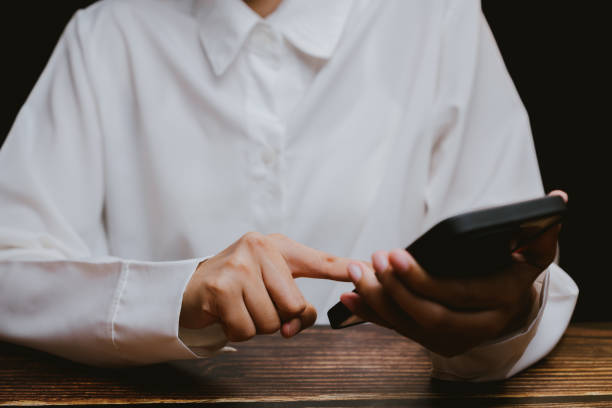 istock Person in White Shirt Using Smartphone with Finger on Screen 2201031146