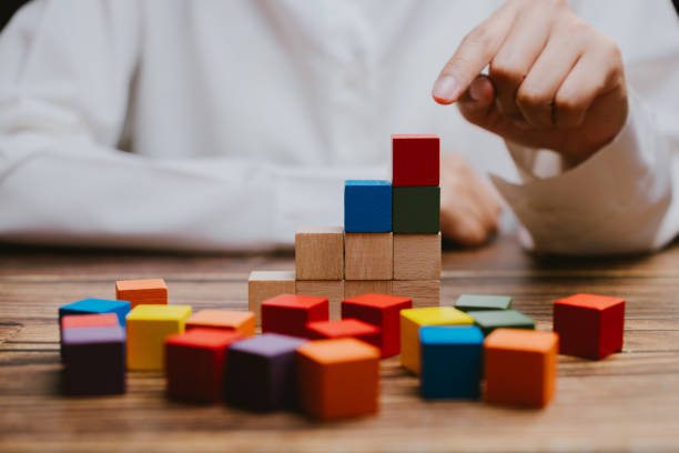 istock Colorful Building Blocks Stacked on Wooden Table by Child's Hand 2201031177