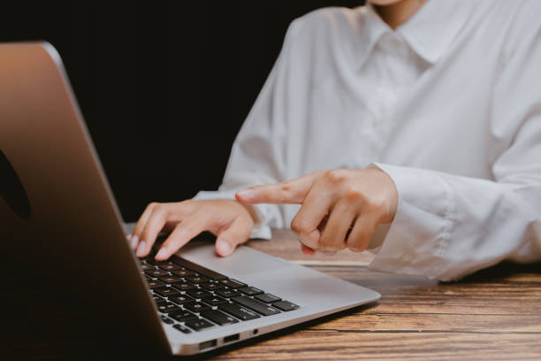 istock Woman in White Shirt Using Laptop with Focused Gesture 2201031320