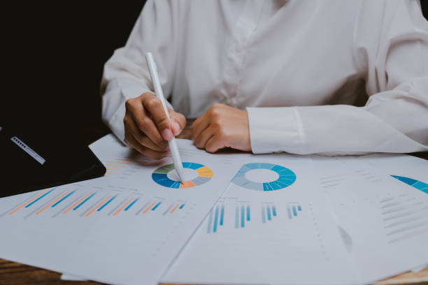 istock Businessperson Analyzing Colorful Graphs and Charts on a Desk 2201031367