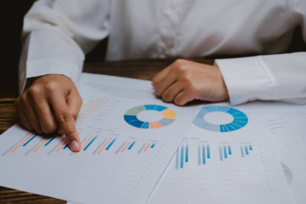 Person Analyzing Business Reports with Graphs and Charts on Table