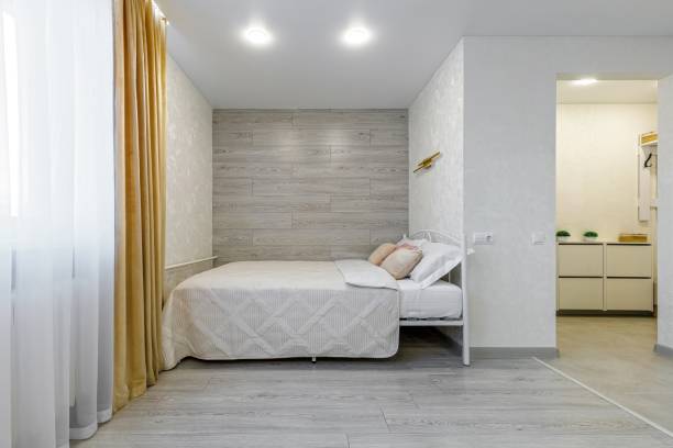 istock Cozy Bedroom with Soft Bedding and Yellow Curtains 2201031509