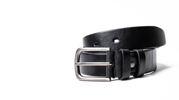 istock Twisted black leather belt with matted metal buckle isolated on white background. Fastened fashionable unisex, man or woman accessory for trousers, jeans, dress. Male luxury strap. Haberdashery goods 2201033748
