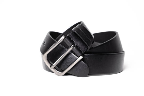 istock Twisted black leather belt with matted metal buckle isolated on white background. Fastened fashionable unisex, man or woman accessory for trousers, jeans, dress. Male luxury strap. Haberdashery goods 2201034769