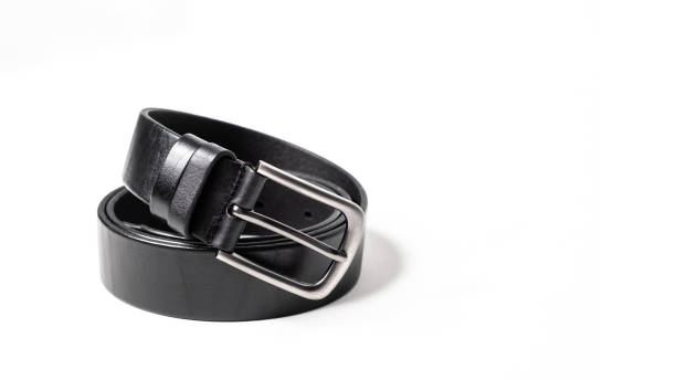 istock Twisted black leather belt with matted metal buckle isolated on white background. Fastened fashionable unisex, man or woman accessory for trousers, jeans, dress. Male luxury strap. Haberdashery goods 2201035907