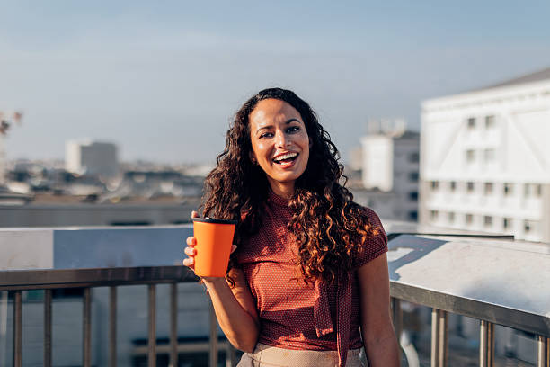 istock Smiling woman holding coffee cup on rooftop 2201037556