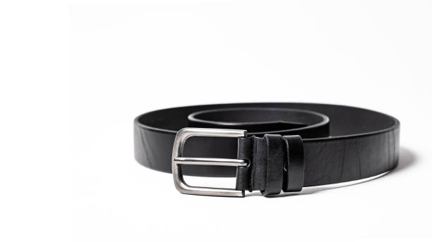istock Twisted black leather belt with matted metal buckle isolated on white background. Fastened fashionable unisex, man or woman accessory for trousers, jeans, dress. Male luxury strap. Haberdashery goods 2201037632
