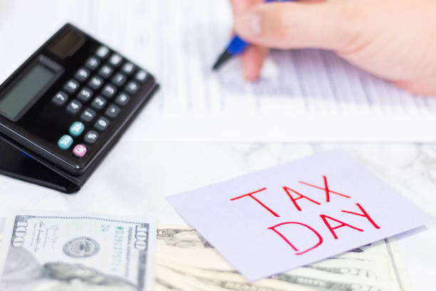 istock Visual representation of tax payment with documents and calculator. Sticky note, US dollars and a person filling out a tax form. 2201041605