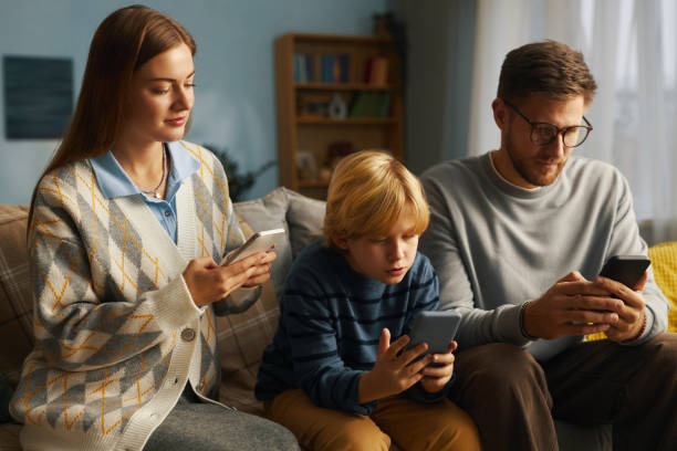 istock Family Sitting on Couch Using Digital Devices at Home 2201045134