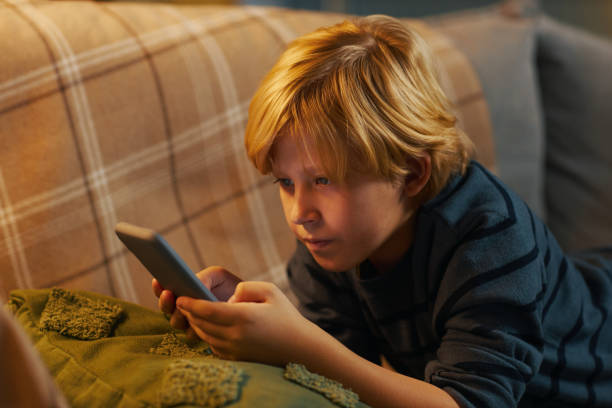 istock Young Boy Engrossed in Holding a Smartphone 2201046782