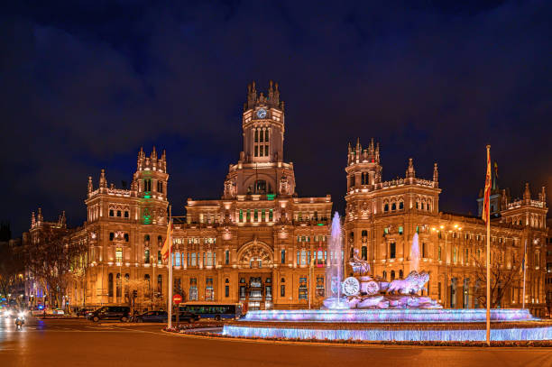 Madrid, Spain - January 25, 2025: Iluminated facade of an old building in the Cibeles Square. The medieval fountain of Cibeles is featured in the image.