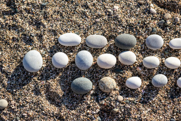 A round pebbles lies in rows on the sand. Top view. High quality photo