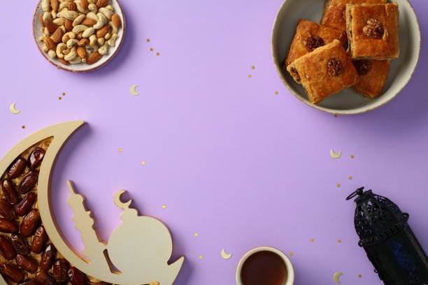 istock Ramadan flat lay composition with traditional sweets, nuts, dates, tea, and lantern on a purple background with crescent moon and star decorations. 2201050068