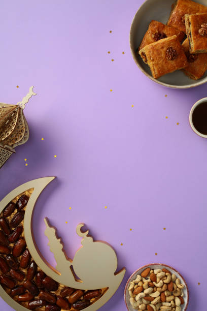 istock Ramadan Kareem concept. Ramadan flat lay with dates, traditional sweets, nuts, and tea cup on a purple background. Crescent moon tray and star decorations. 2201050208
